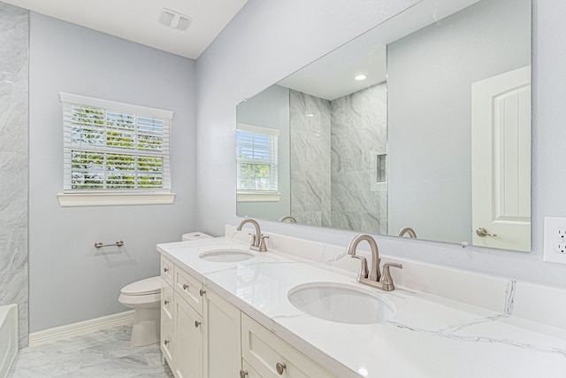 bathroom with tiled shower, vanity, and toilet