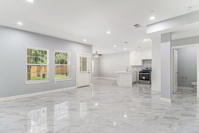 unfurnished living room featuring ceiling fan and sink