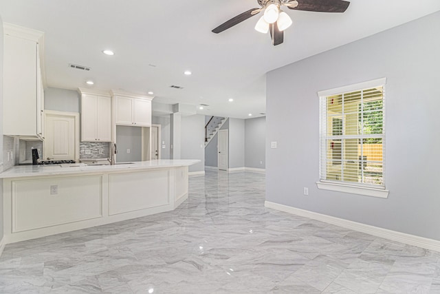 kitchen featuring tasteful backsplash, kitchen peninsula, white cabinetry, and ceiling fan