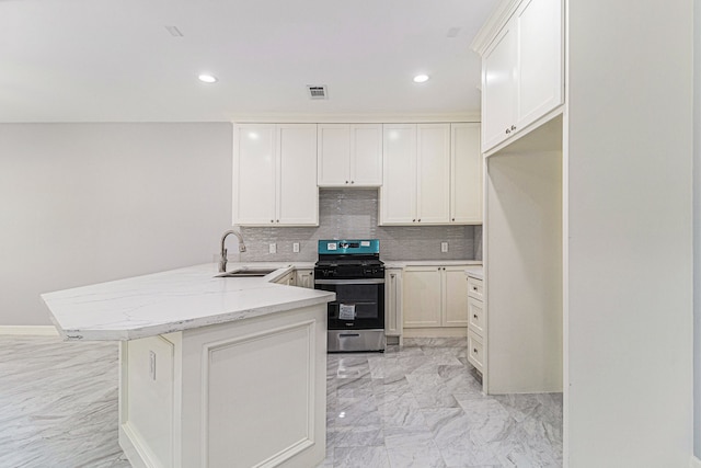 kitchen featuring sink, stainless steel stove, decorative backsplash, light stone counters, and kitchen peninsula