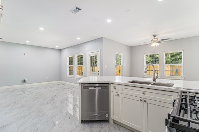 kitchen featuring light stone countertops, ceiling fan, sink, dishwasher, and range