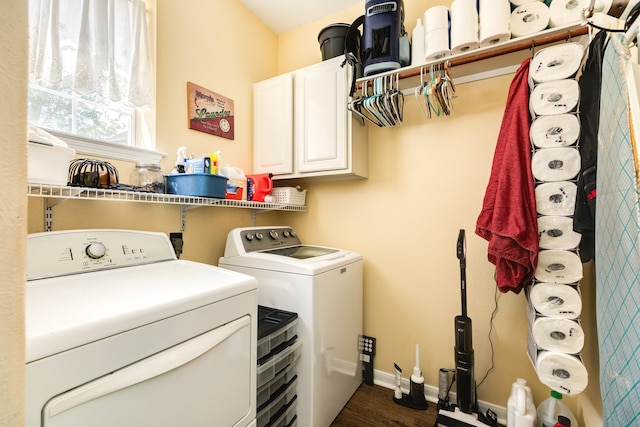 clothes washing area with washing machine and clothes dryer, cabinets, and dark wood-type flooring