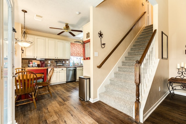 kitchen featuring dark wood-type flooring, white cabinets, pendant lighting, ceiling fan, and stainless steel dishwasher