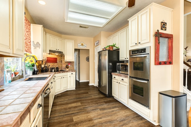 kitchen with sink, backsplash, tile countertops, stainless steel appliances, and dark hardwood / wood-style flooring