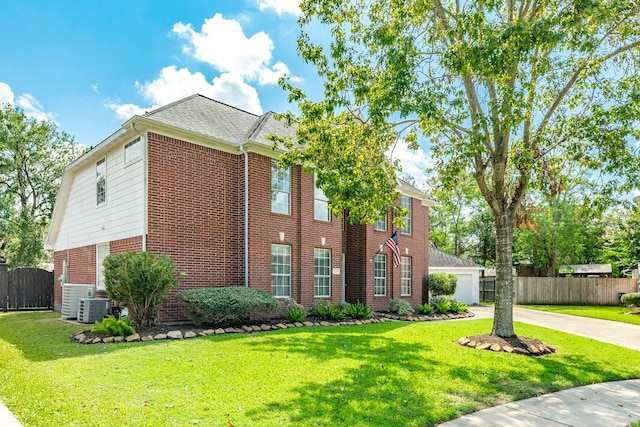 view of front of home featuring a front lawn, central AC unit, and a garage