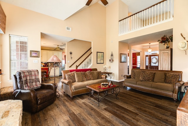 living room featuring ceiling fan, a towering ceiling, and dark wood-type flooring