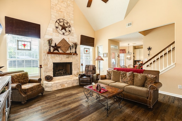 living room featuring a stone fireplace, ceiling fan, dark wood-type flooring, and high vaulted ceiling