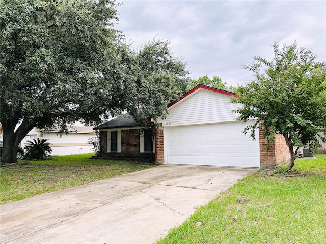 view of front of property with a garage, a front lawn, and central AC