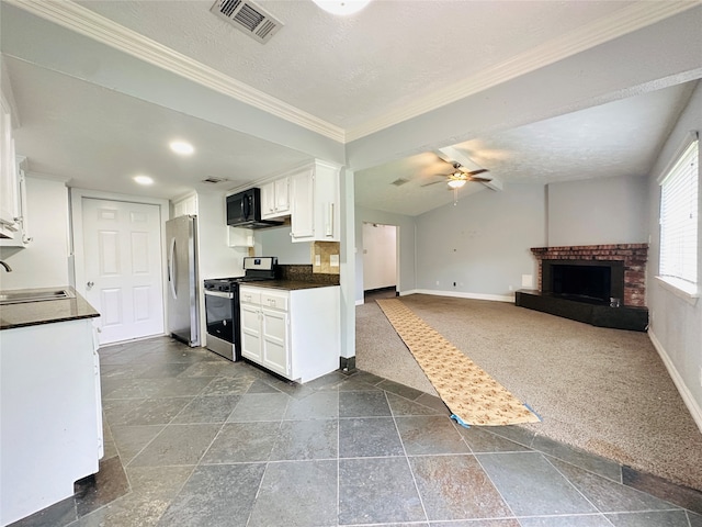 kitchen with a brick fireplace, ceiling fan, stainless steel appliances, and white cabinets