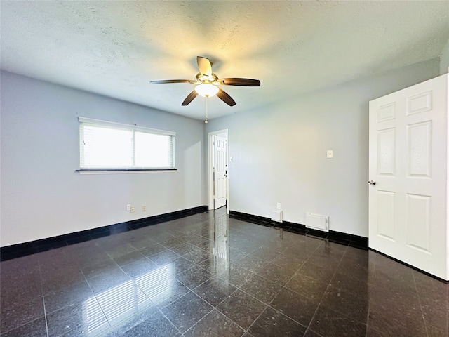 unfurnished room with ceiling fan and a textured ceiling