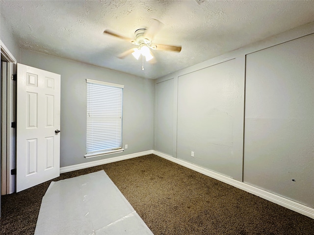 spare room featuring ceiling fan, a textured ceiling, and dark colored carpet