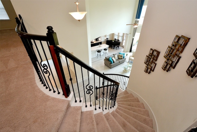 staircase featuring carpet flooring and a high ceiling