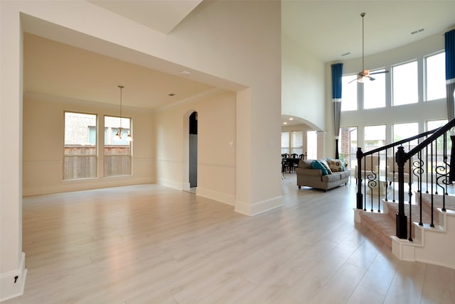 interior space with ceiling fan, plenty of natural light, light hardwood / wood-style floors, and a high ceiling