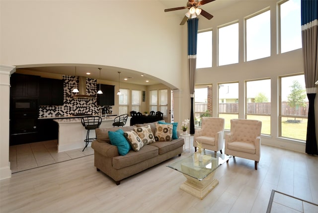 living room with light hardwood / wood-style floors, a high ceiling, and ceiling fan