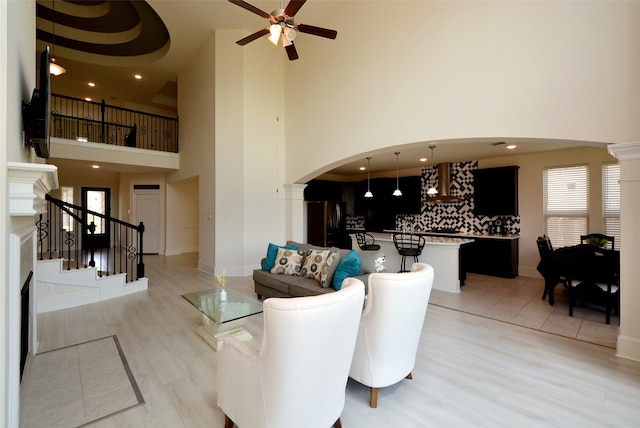 living room featuring light hardwood / wood-style flooring, a high ceiling, and ceiling fan