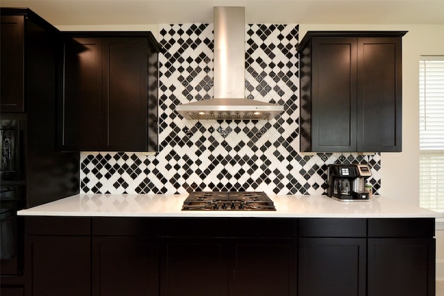 kitchen with black appliances, wall chimney range hood, and tasteful backsplash