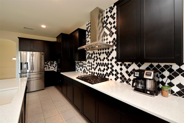 kitchen with light stone counters, tasteful backsplash, gas cooktop, light tile patterned floors, and stainless steel fridge