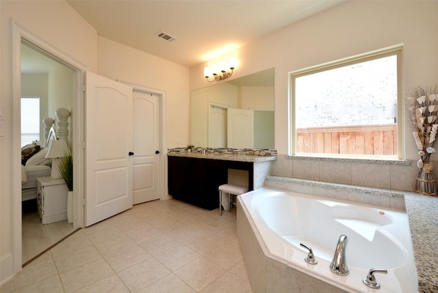 bathroom featuring tiled tub, vanity, and tile patterned floors