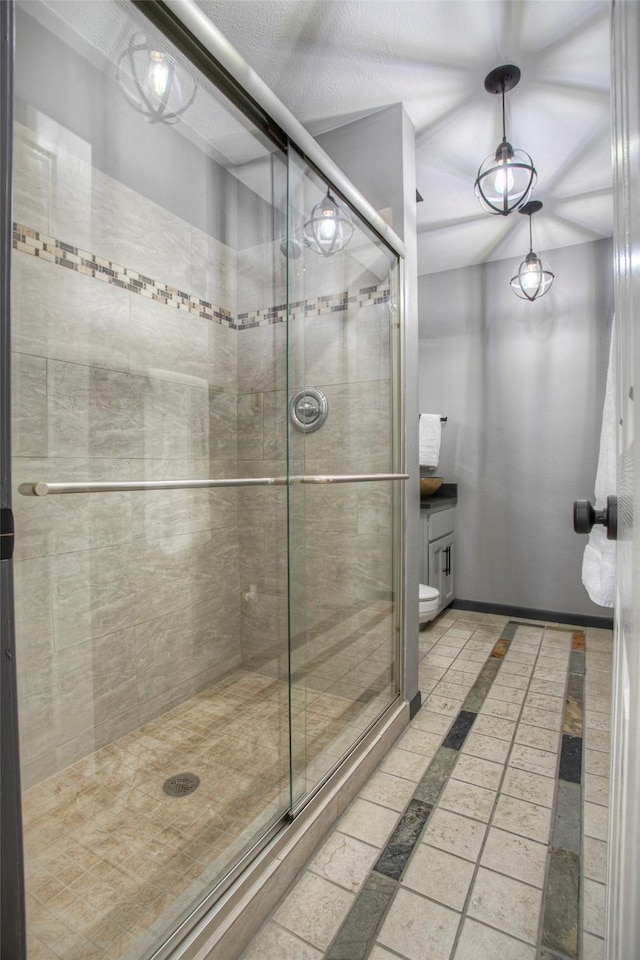 bathroom featuring a stall shower, vanity, toilet, and baseboards