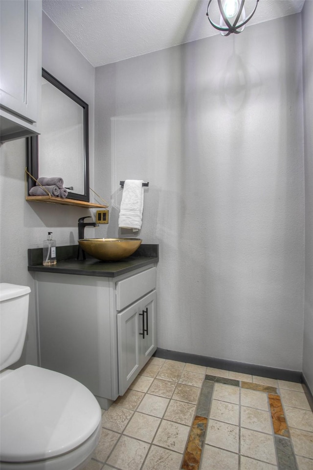 bathroom with vanity, toilet, and a textured ceiling