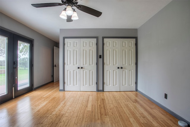 unfurnished bedroom featuring french doors, light wood-type flooring, two closets, access to outside, and ceiling fan