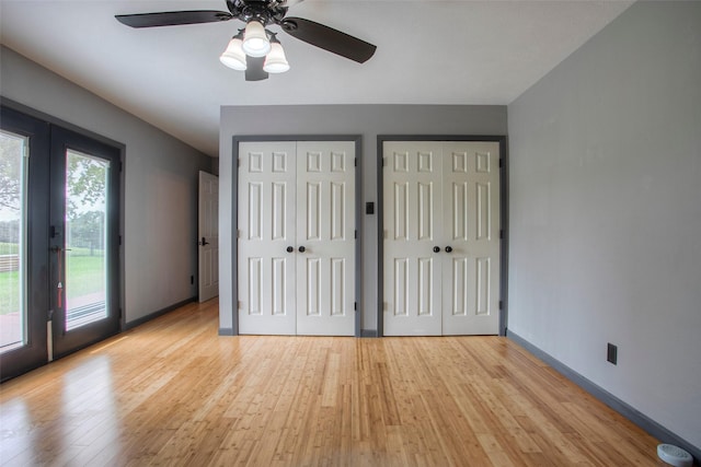 unfurnished bedroom featuring access to outside, light wood finished floors, two closets, and french doors