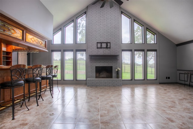 tiled living room featuring ceiling fan, a fireplace, high vaulted ceiling, and a healthy amount of sunlight