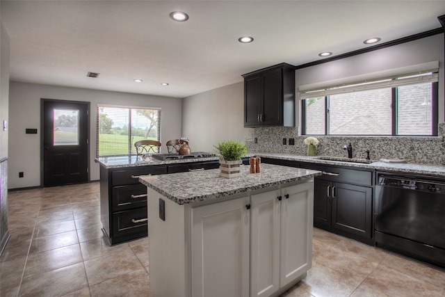 kitchen with light stone countertops, dishwasher, a center island, sink, and decorative backsplash