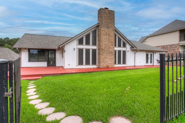 rear view of house with a lawn, a wooden deck, and french doors