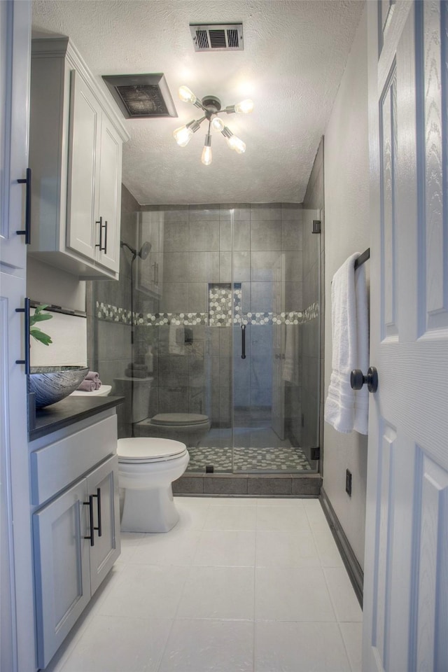 full bathroom with a stall shower, visible vents, a textured ceiling, and toilet