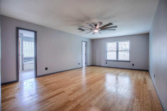 empty room featuring light wood-style floors, plenty of natural light, baseboards, and a ceiling fan