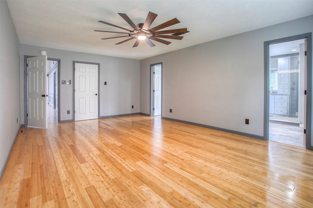 empty room featuring ceiling fan, light wood-style flooring, and baseboards