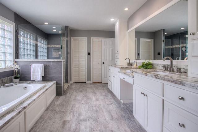 bathroom with a closet, a shower stall, vanity, and a bath