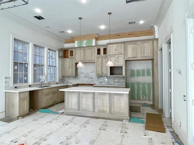 kitchen with decorative light fixtures, a kitchen island, sink, tasteful backsplash, and crown molding