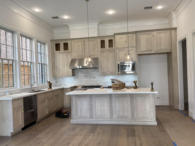 kitchen featuring visible vents, stainless steel microwave, a kitchen island, a sink, and under cabinet range hood