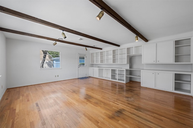 unfurnished living room featuring hardwood / wood-style flooring, track lighting, and beam ceiling