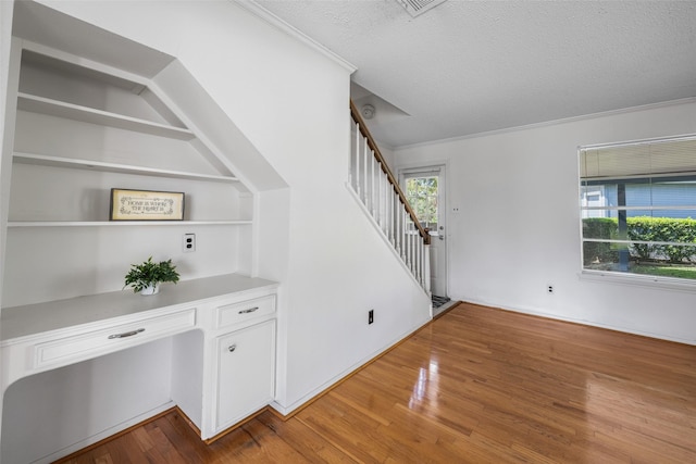 interior space with hardwood / wood-style floors, a textured ceiling, built in desk, and a healthy amount of sunlight