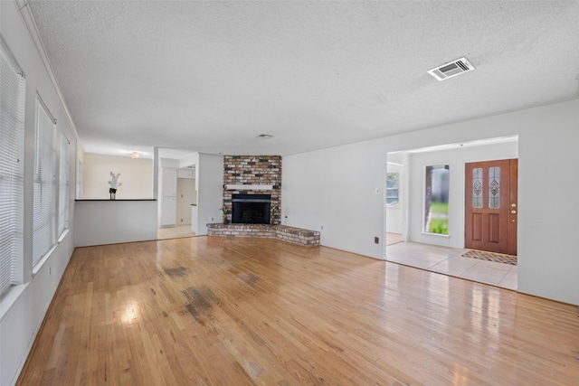 unfurnished living room featuring a fireplace, light hardwood / wood-style flooring, and a textured ceiling