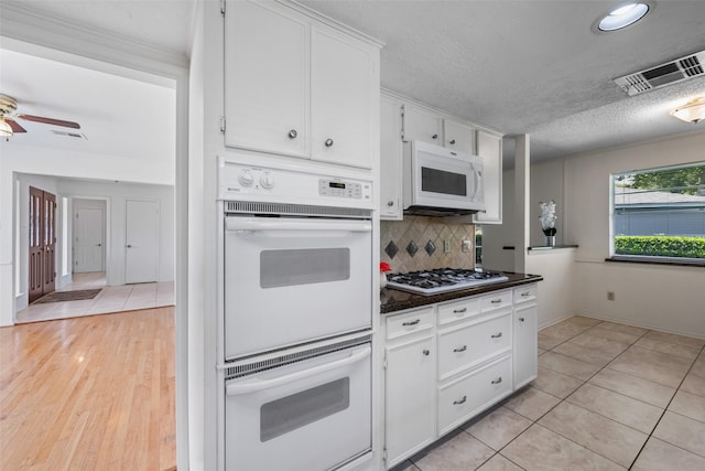 kitchen featuring white cabinetry, white appliances, a textured ceiling, and backsplash