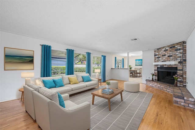 living room featuring a fireplace, light hardwood / wood-style floors, and a textured ceiling