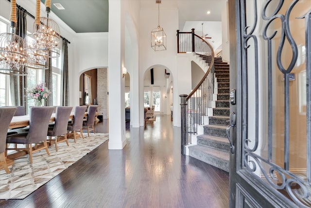 entryway featuring a towering ceiling, dark wood-type flooring, a chandelier, and a healthy amount of sunlight