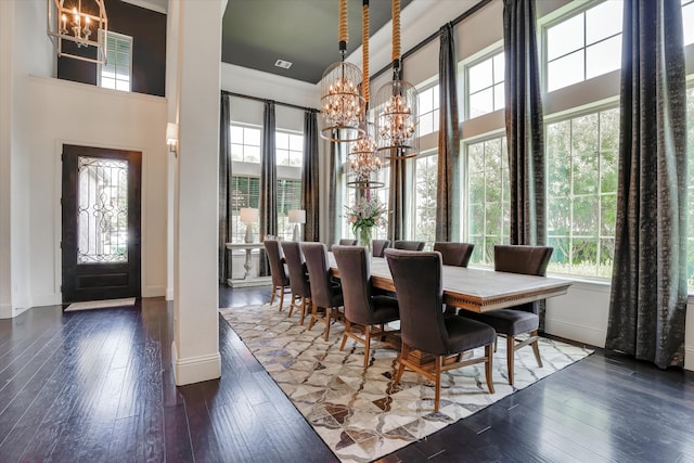 dining room featuring a notable chandelier, a towering ceiling, and dark wood-type flooring