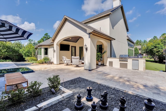 back of property featuring a patio and an outdoor kitchen