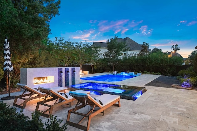 pool at dusk featuring a patio and exterior fireplace