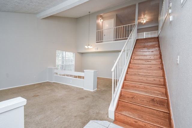 stairway with beamed ceiling, carpet flooring, a textured ceiling, a chandelier, and a towering ceiling