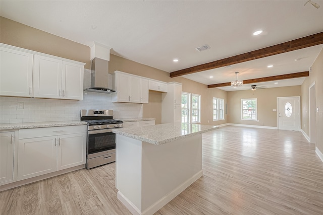 kitchen with white cabinets, backsplash, beamed ceiling, light wood-type flooring, and stainless steel range with gas stovetop