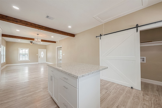 kitchen with white cabinets, beamed ceiling, a kitchen island, light wood-type flooring, and a barn door