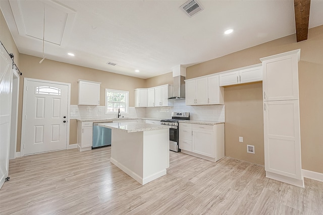 kitchen featuring appliances with stainless steel finishes, wall chimney exhaust hood, light wood-type flooring, and white cabinetry