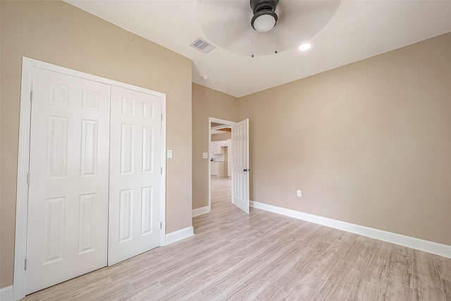 unfurnished bedroom with light wood-type flooring, ceiling fan, and a closet