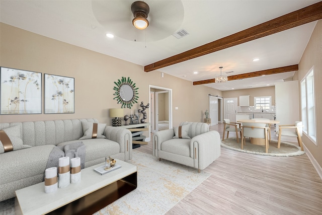 living room with ceiling fan, beamed ceiling, and light wood-type flooring